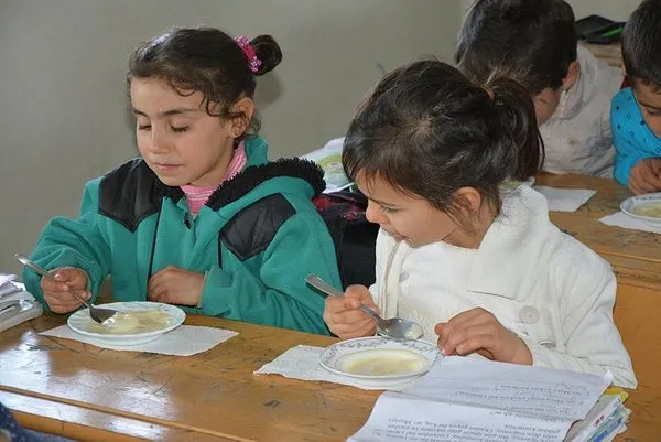 Öğrencilerine odun sobasında puding hazırlıyor