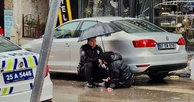 Polis memuru, yaralının başında şemsiye ile bekledi