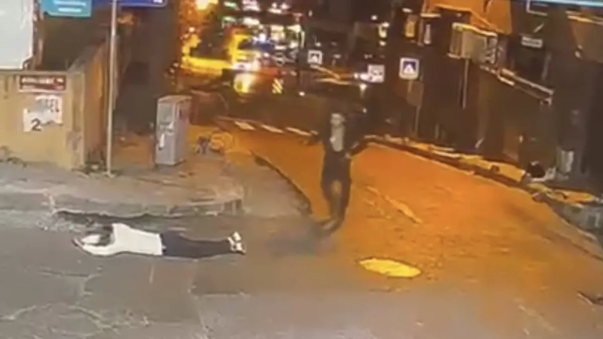 Şişli'de bir iş yerine silahlı saldırı düzenleyen tetikçi, bekçi tarafından ayağından vurulduktan sonra yere yığılmış halde.
