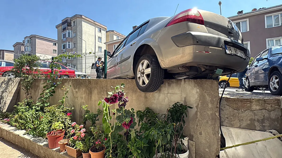 Çorlu'da el freni çekilmeyen otomobil apartman bahçe duvarında asılı kaldı.