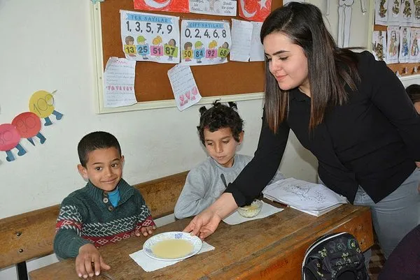Öğrencilerine odun sobasında puding hazırlıyor