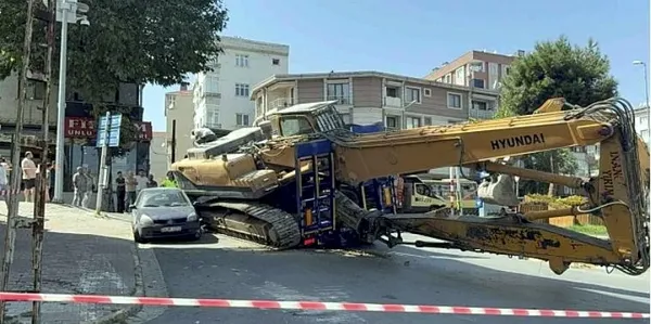 bina-yikimi-icin-getirilen-tirin-uzerindeki-is-makinesi-otomobilin-uzerine-devrildi-sans-eseri-yaralanan-olmad-1755891154625.jpg